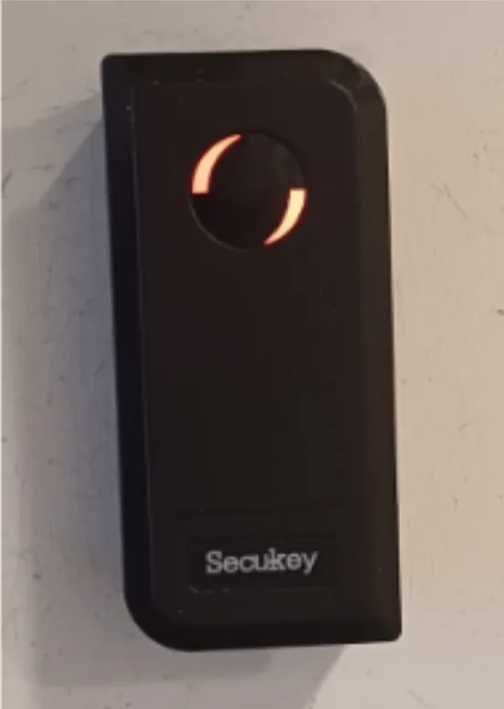 The black Secukey badge reader next to the door