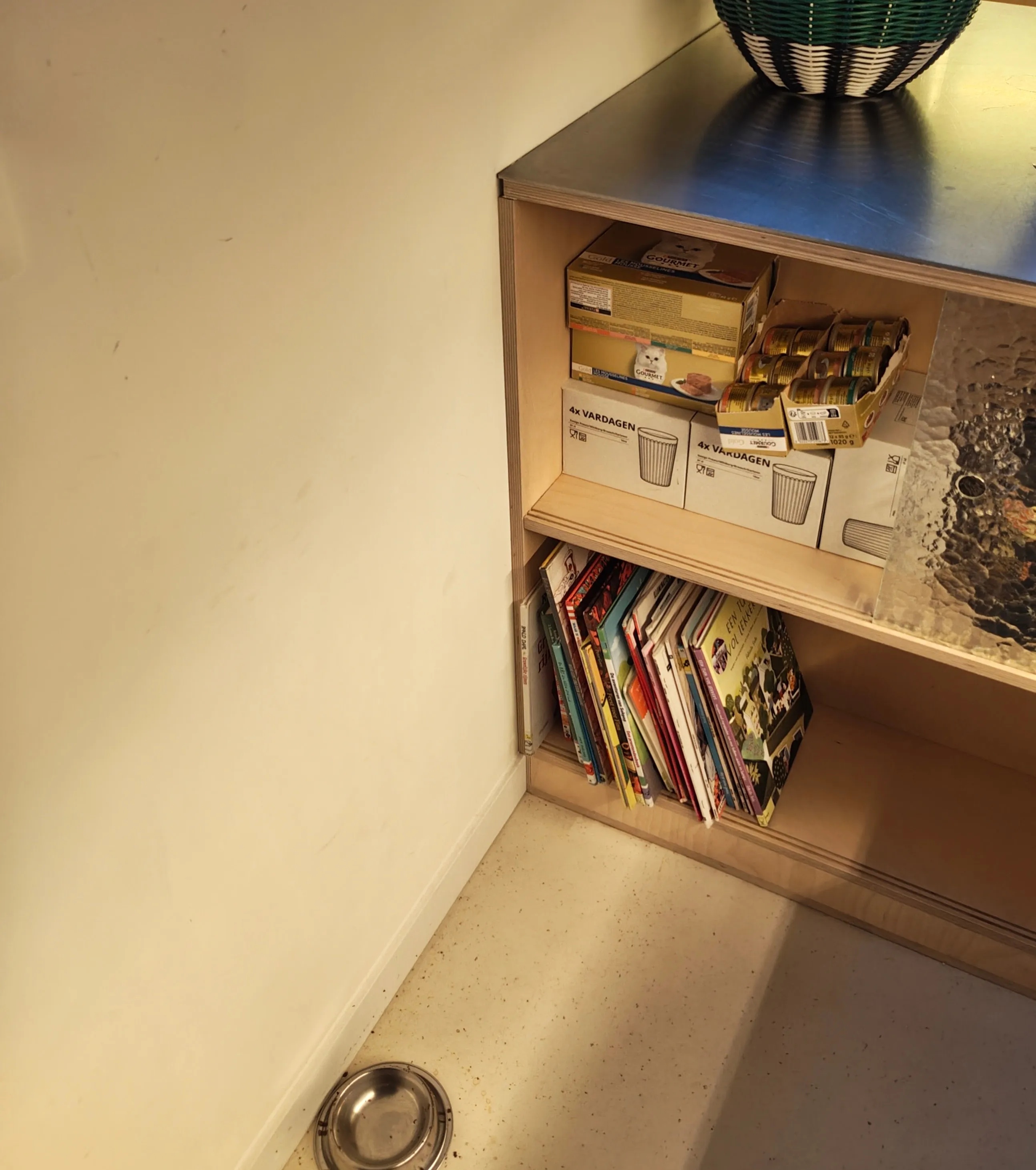 The cupboard with the glass sliding door where the tins of wet food are kept